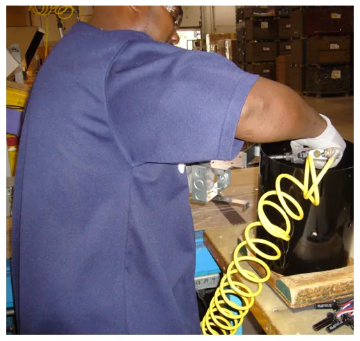 RULA example task: a worker reaching into a large metal can with a pneumatic screwdriver at a workbench